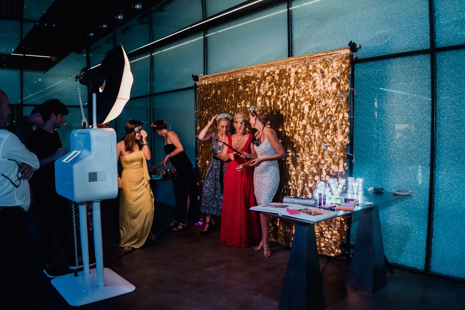 Invitados de boda posando ante la pared dorada con el fotomatón de Smybox