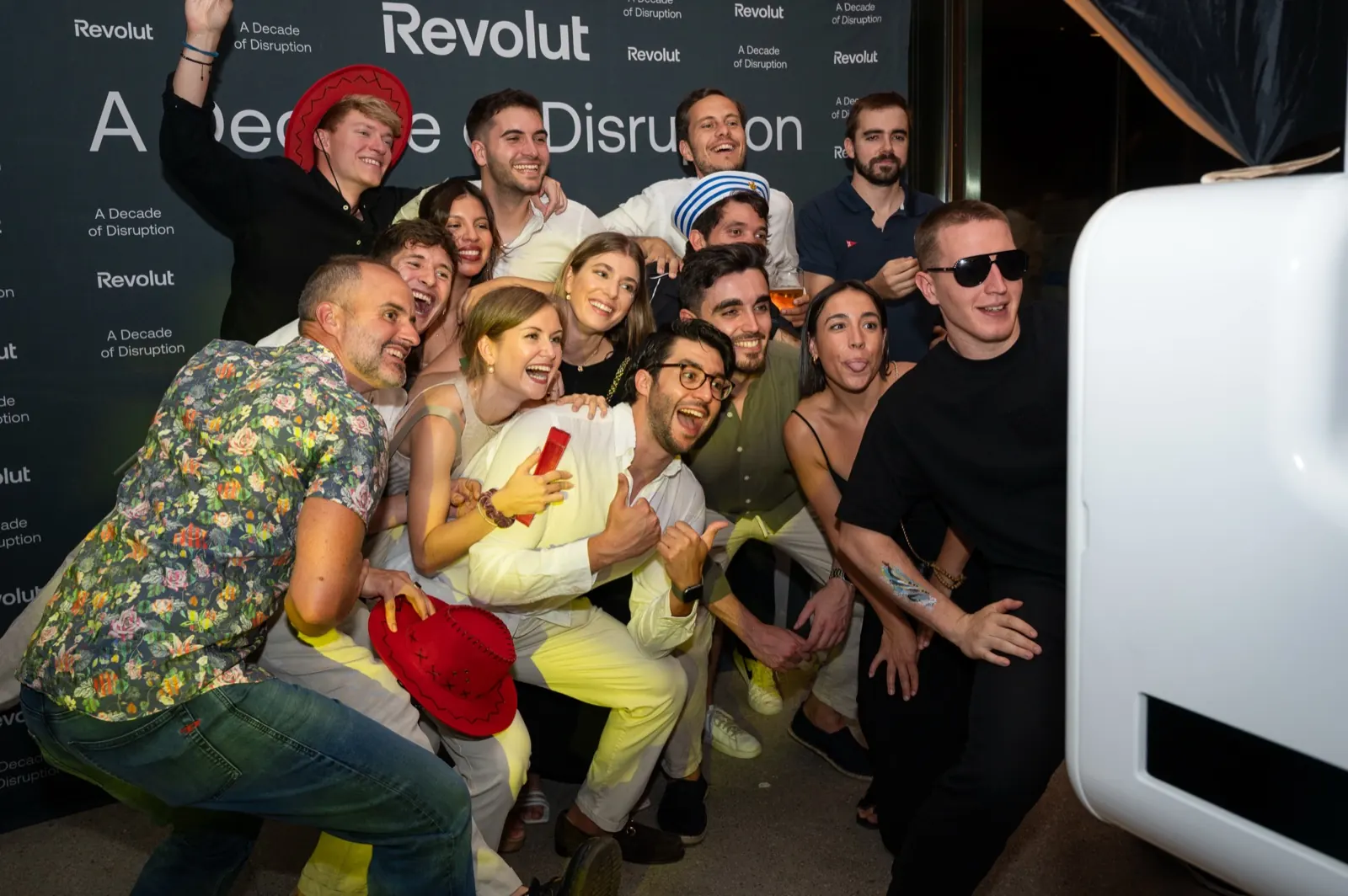 Invitados de la fiesta de Revolut posando ante la pared de marca del fotomatón de Smybox