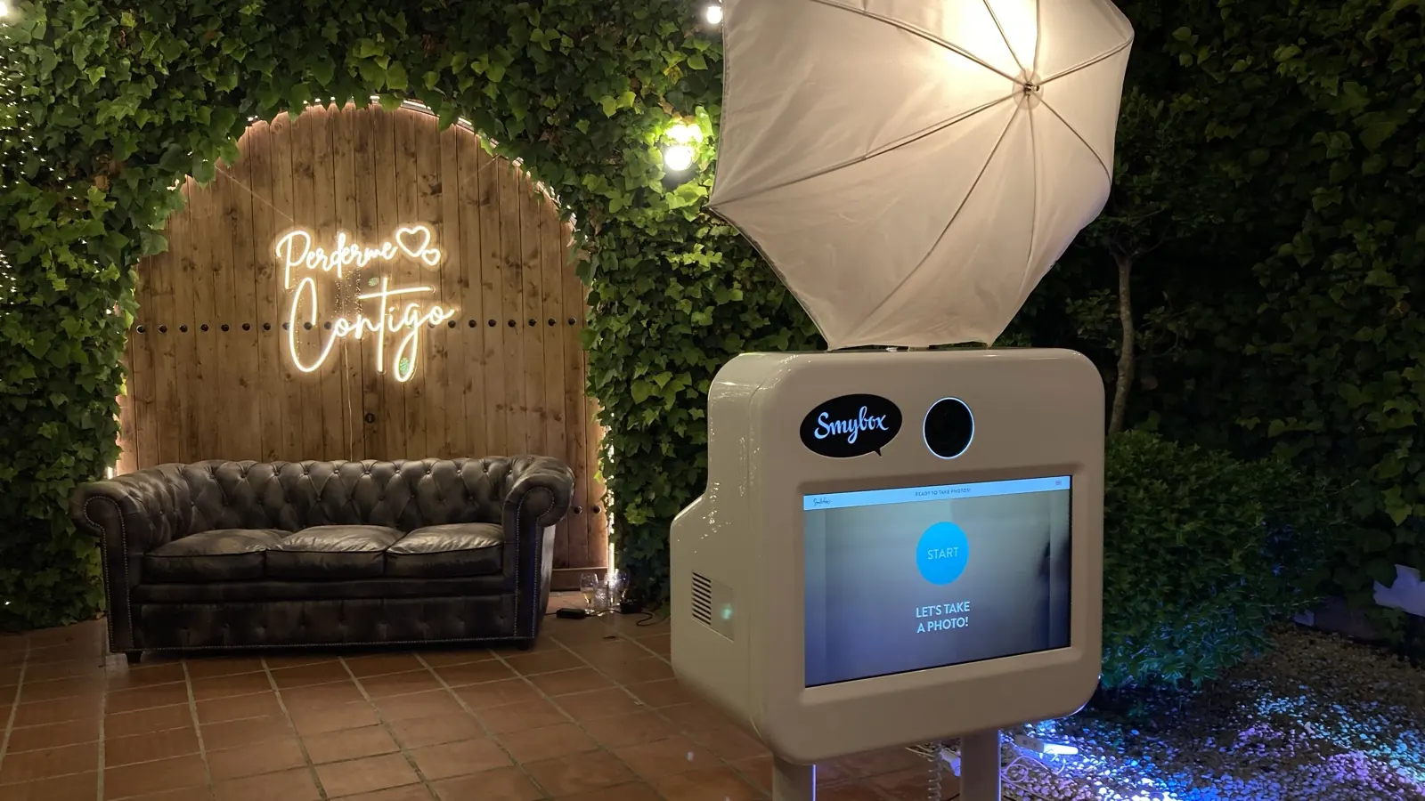 Rincón de jardín con cartel de neón y el fotomatón de Smybox en una fiesta privada